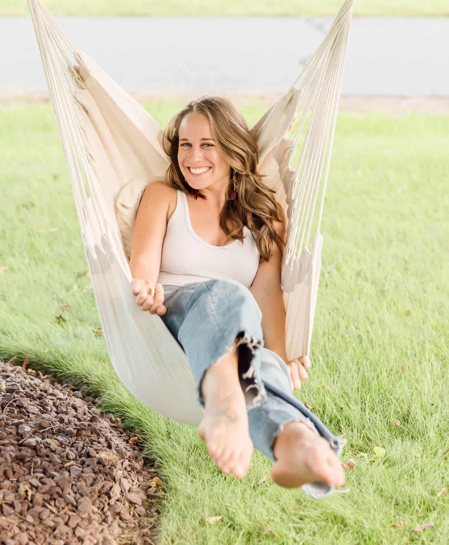 Kylie of Strata Nutrition smiles and playfully swings in a cloth chair hanging from a tree